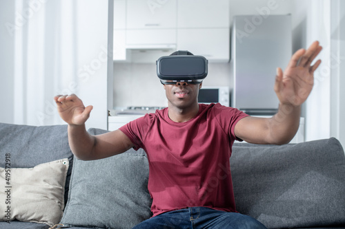 A dark-skinned young man sitting in VR glasses