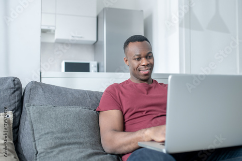 Obraz na plátně A dark-skinned young man working from home and looking involved