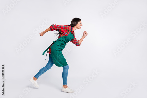 Full size profile side photo of happy young woman run empty space delivery work isolated on grey color background