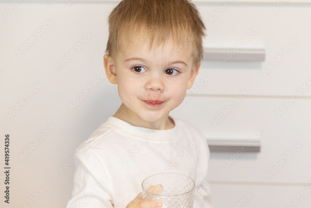 The child drinks water from a glass. Selective focus. The child drinks water from a glass. Selective focus.