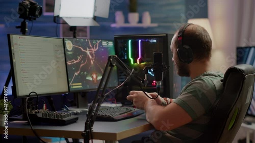 Pro cyber streamer losing videogame tournament while wearing professional headset holding wireless controller. Defeated gamer using joystick for online competition late at night in gaming room