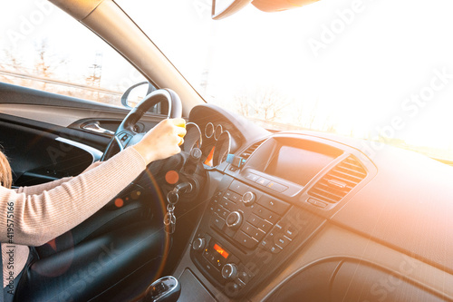 Driver training car on road in winter sunny day. Happy young woman inside vehicle driving. Vacation ride trip travel concept.