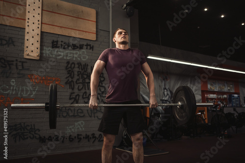 Strong male athlete lifting barbell at cross fit gym