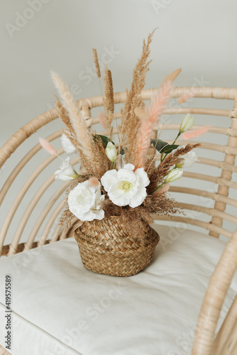 artificial decorative flowers in a wicker basket on an armchair