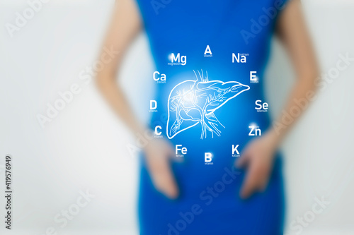 Graphic visualization of healthy human liver surrounded with icons of vitamins and minerals. Blurred female figure, positive blue bright color of recovery, health and detox concept. photo