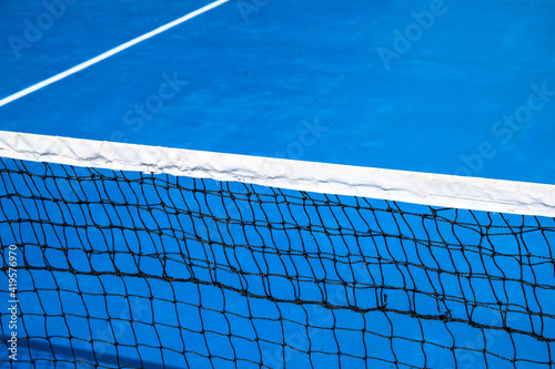 Blue tennis court with net. Empty sport field photo. Hard court for lawn tennis. Summer sport activity game outdoor. White markup on blue court. Sunny day on tennis court. Sport field in park