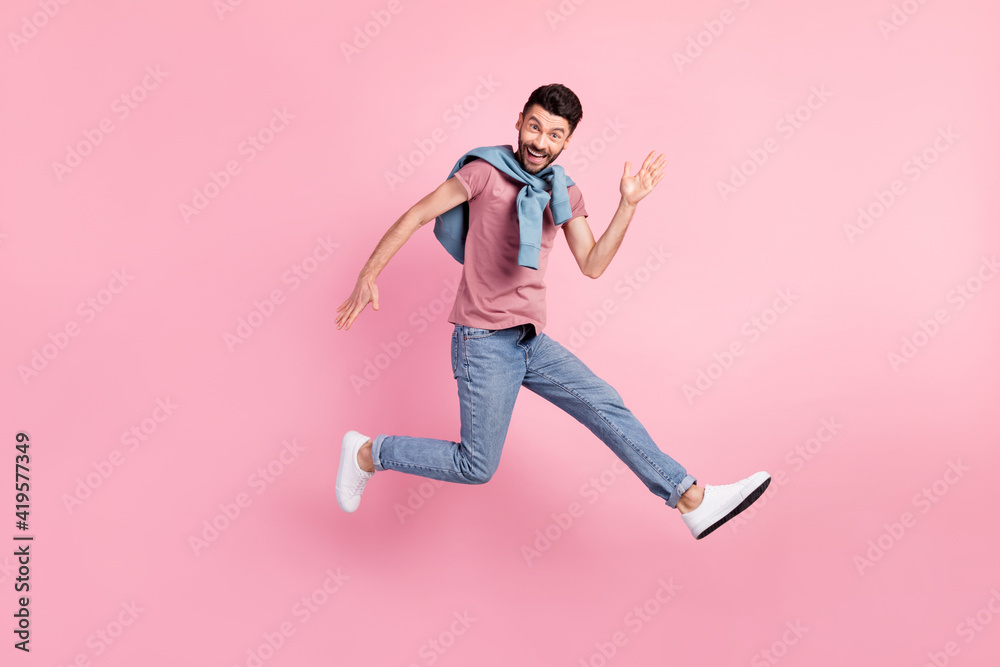 Full size photo of happy cheerful smiling handsome man running in air say hello isolated on pink color background