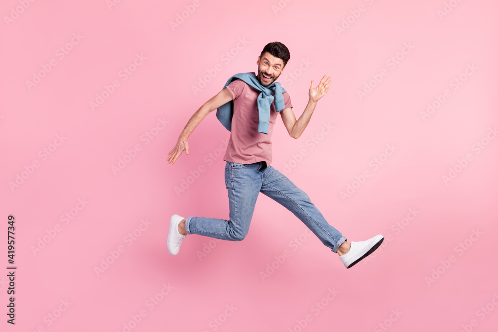 Full size photo of happy cheerful smiling handsome man running in air say hello isolated on pink color background Full size photo of happy cheerful smiling handsome man running in air say hello isolated on pink color background