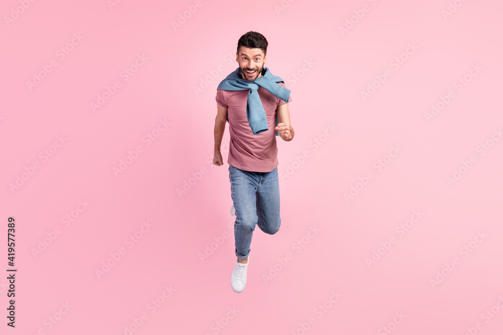 Full size photo of handsome positive good mood man running fast speed in air fly isolated on pink color background Full size photo of handsome positive good mood man running fast speed in air fly isolated on pink color background