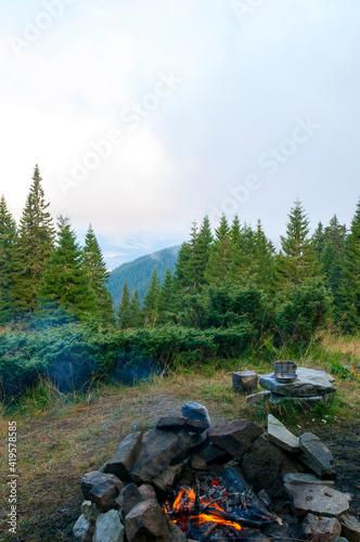 fire near the tent in the mountains on a background of green forest