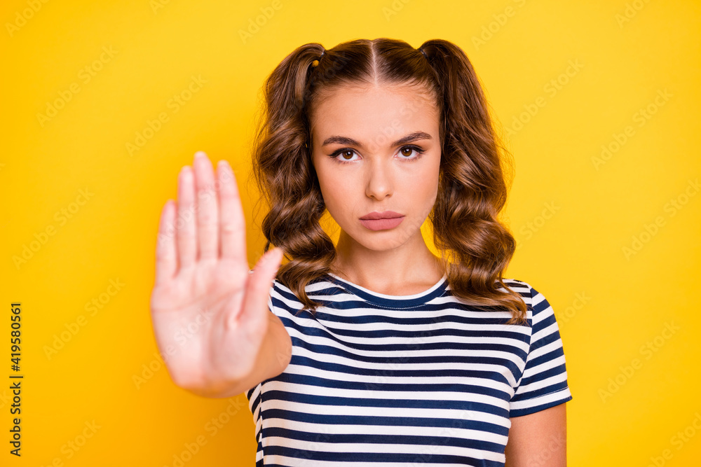 Portrait of attractive strict serious girl showing palm stop sign dont move caution isolated on bright yellow color background Portrait of attractive strict serious girl showing palm stop sign dont move caution isolated on bright yellow color background