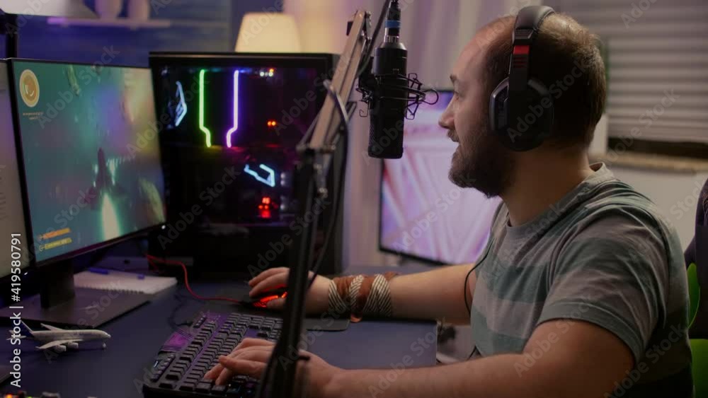 Winner streamer playing online space shooter game in gaming room using RGB keyboard and system desktop. Cyber performing on powerful pc talking with players on chat open during live competition Winner streamer playing online space shooter game in gaming room using RGB keyboard and system desktop. Cyber performing on powerful pc talking with players on chat open during live competition