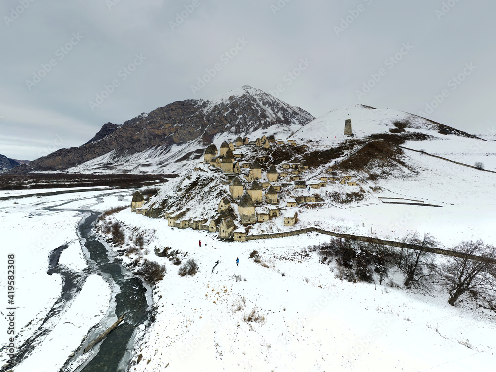 a panoramic view from a drone of an ancient fortress in the snow-capped mountains of Ingushetia 