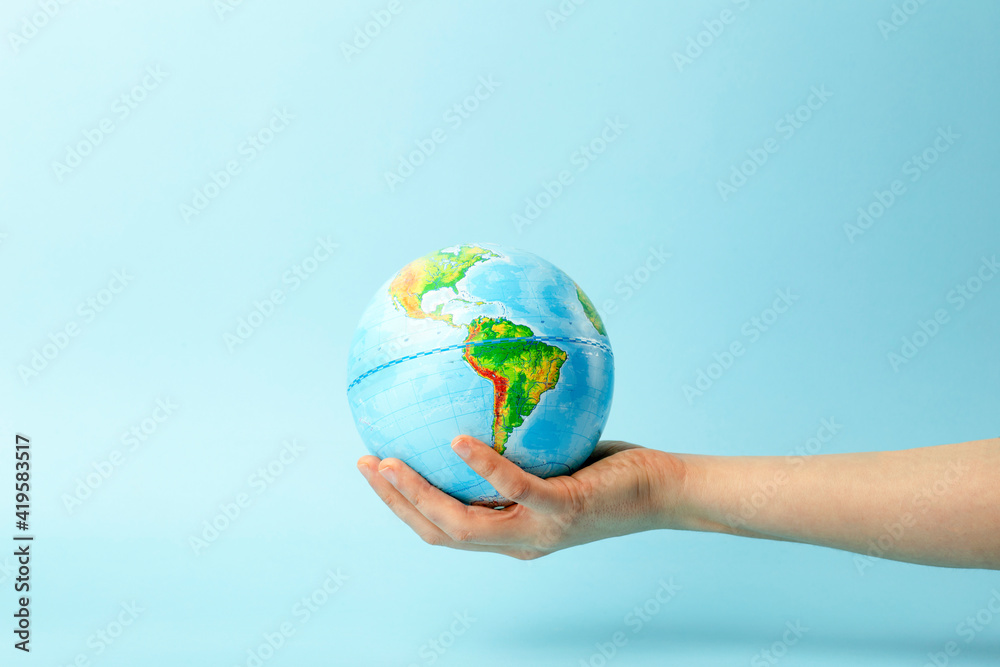 Earth globe in hands on a clean blue background. The concept of protecting nature, ecology and global peace Earth globe in hands on a clean blue background. The concept of protecting nature, ecology and global peace