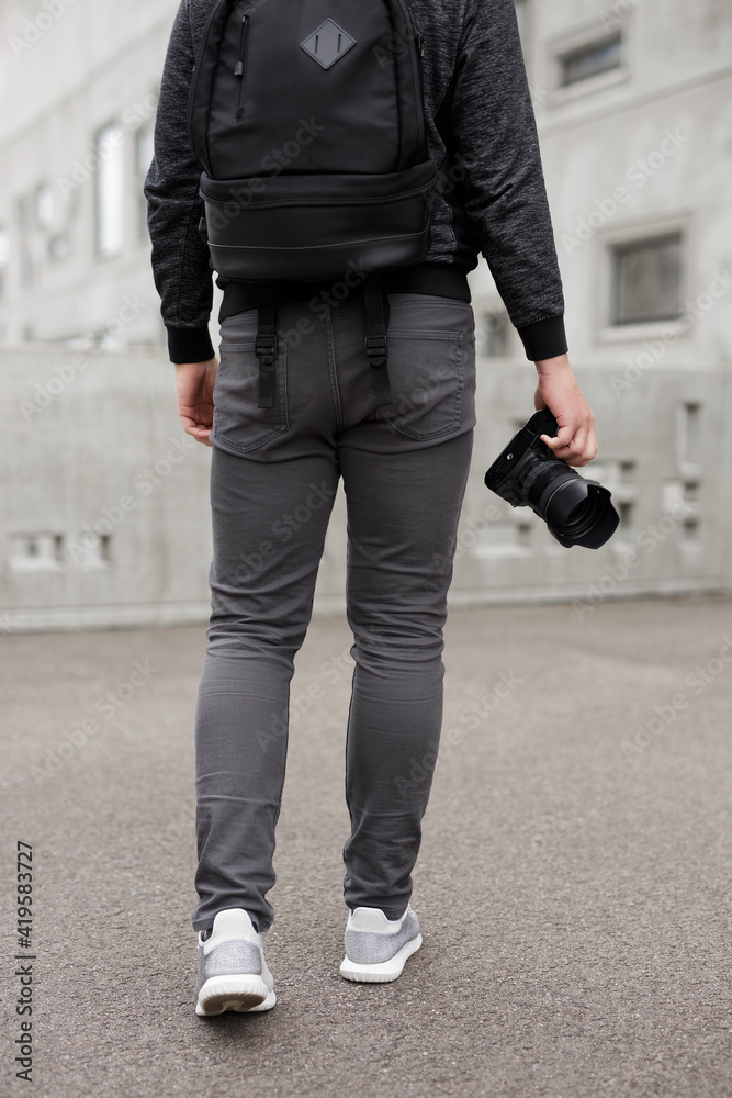back view of male photographer with modern dslr camera over concrete building background