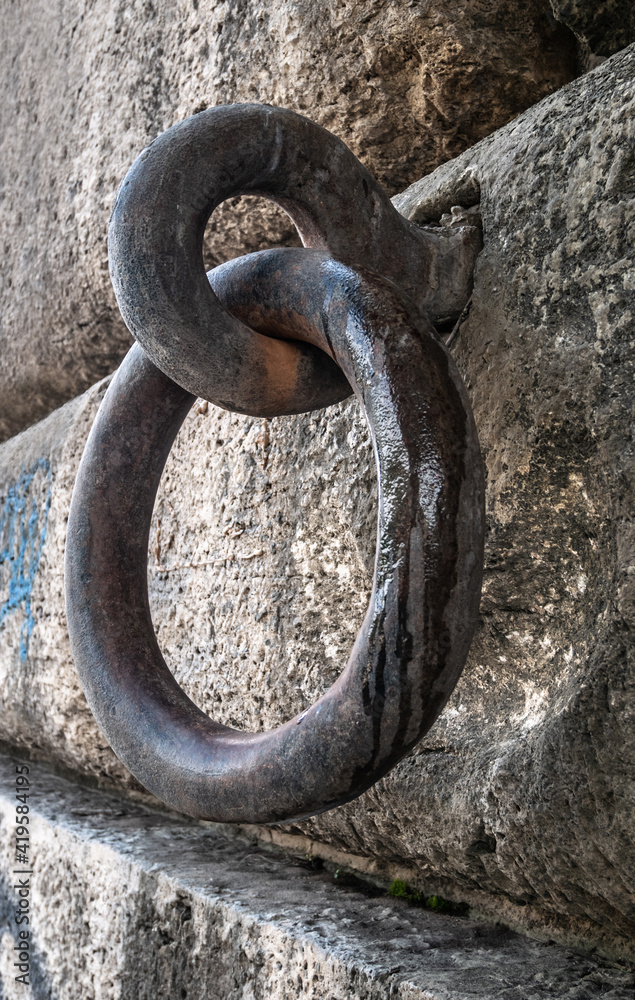 Old and rusty steel mooring ring attached to a stone wall. Old and rusty steel mooring ring attached to a stone wall.