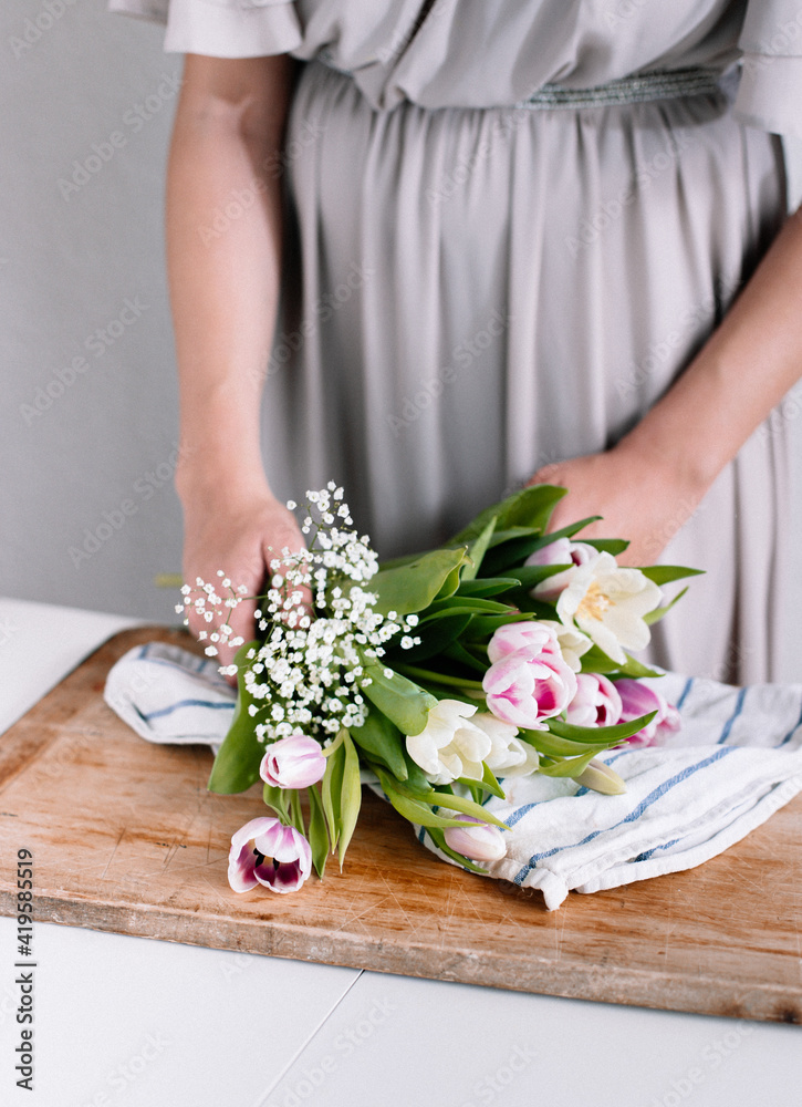 Woman holding flowers in a brown cutting board, for Nordic feeling and vibes. 