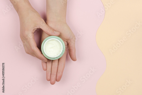 An open jar of cream in a woman's hand. Organic cosmetics for skin care. Beauty concept