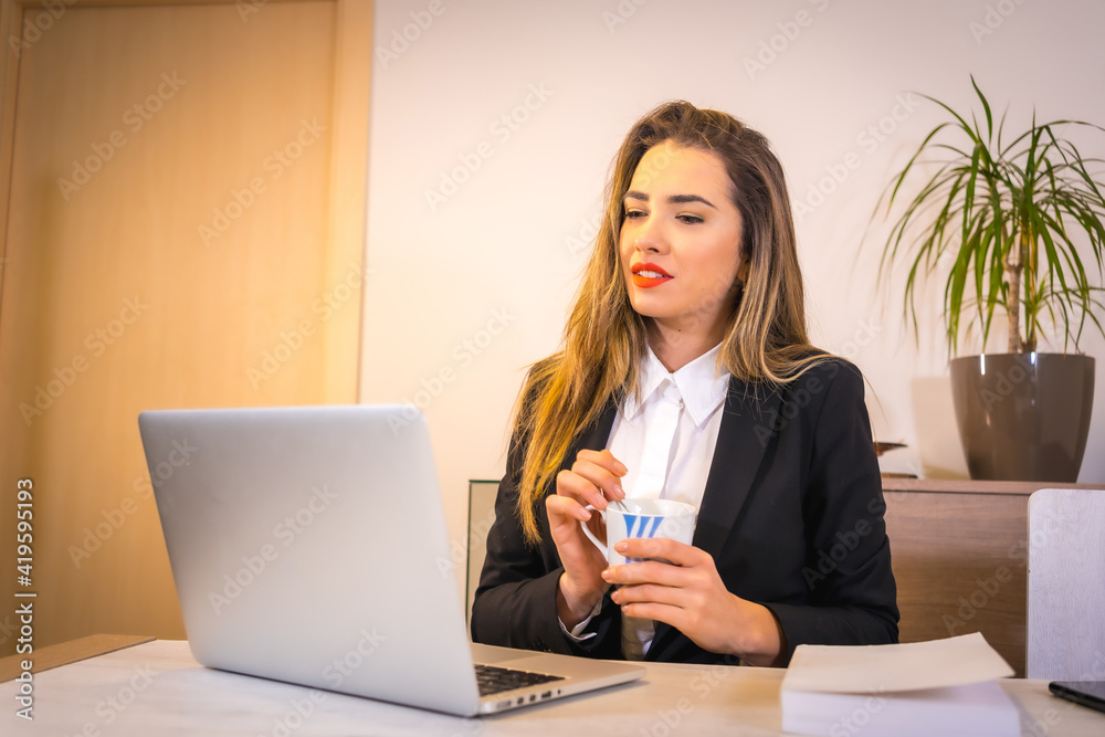 Teleworking at home during the coronavirus pandemic, young blonde Caucasian woman with a coffee very attentive in the online meeting Teleworking at home during the coronavirus pandemic, young blonde Caucasian woman with a coffee very attentive in the online meeting