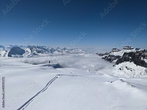  Ski tour in the Swiss mountains. View of the snowy mountains above the clouds. Fantastic views and a powder run. Glarus. Skimo © SimonMichael