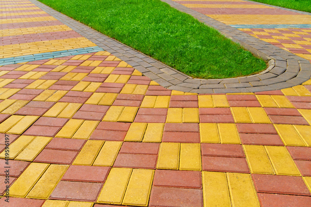 Obraz premium walkway made of paving slabs and green grass as a background, bright sunlight