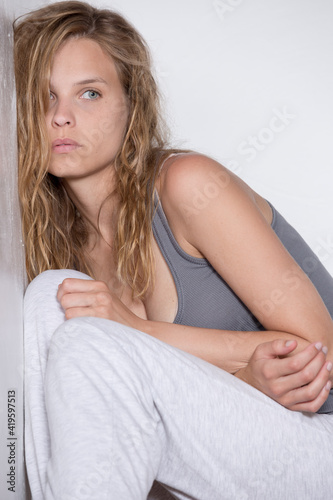 young sad woman in casual clothes very alone at home sitting on stairs