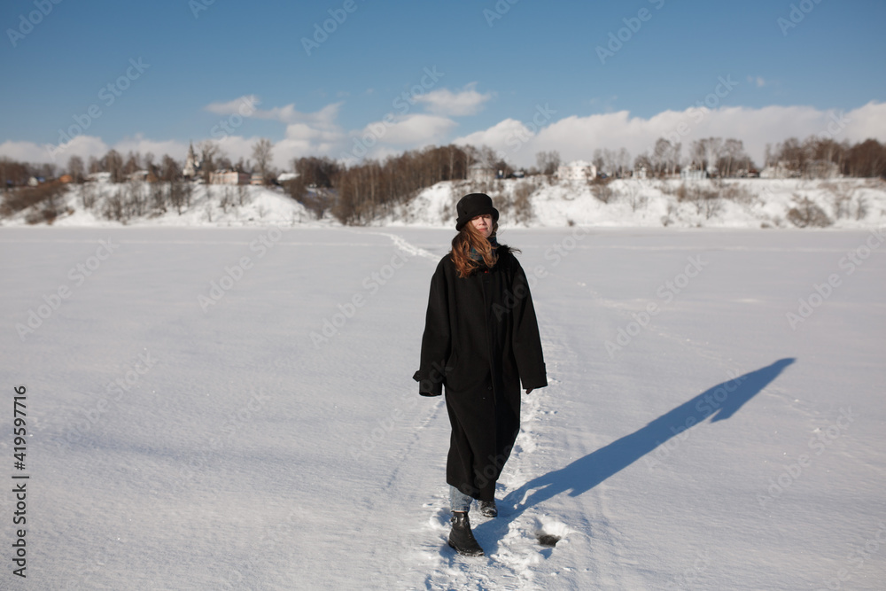 Girl in the winter in the field. Sunny blue day and a girl.
