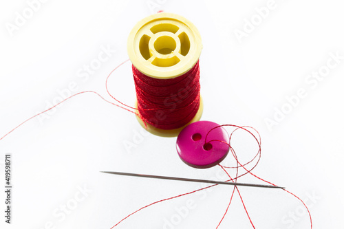 Button with two holes. Thin red thread.