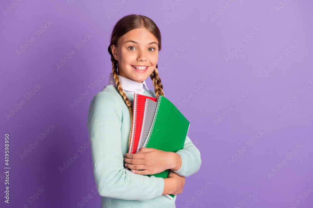 Photo portrait of cute girl holding copybooks isolated on vivid purple colored background witb blank space Photo portrait of cute girl holding copybooks isolated on vivid purple colored background witb blank space