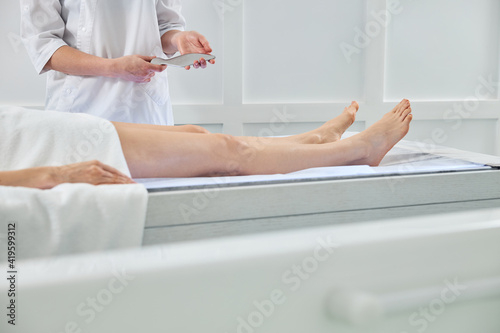 Masseuse standing near client and holding metal tool