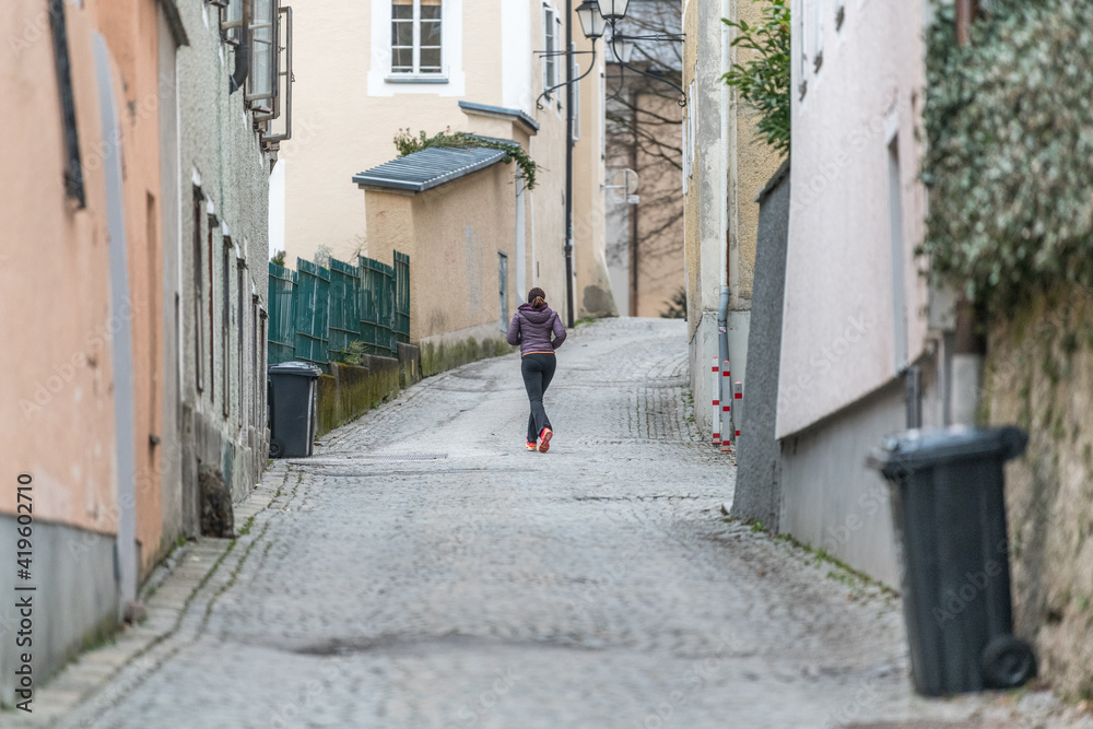 Joggerin läuft durch historische Gasse in Salzburg Joggerin läuft durch historische Gasse in Salzburg