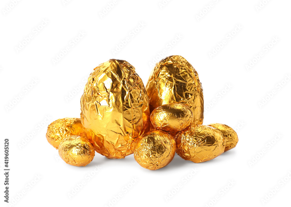 Chocolate eggs wrapped in golden foil on white background Chocolate eggs wrapped in golden foil on white background