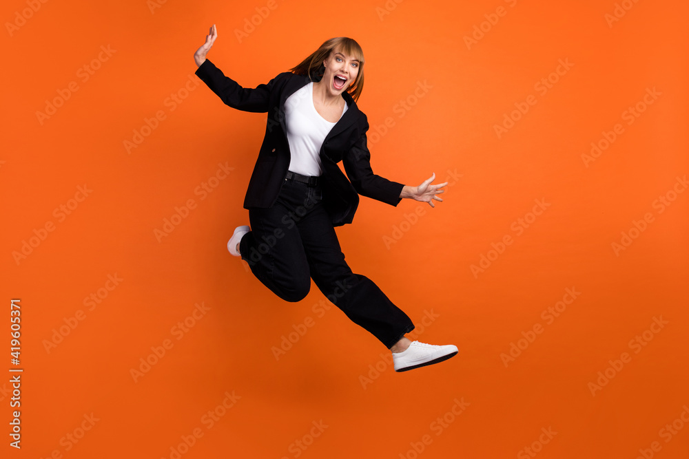 Full size photo of happy excited smiling good mood crazy lovely woman jumping screaming isolated on orange color background
