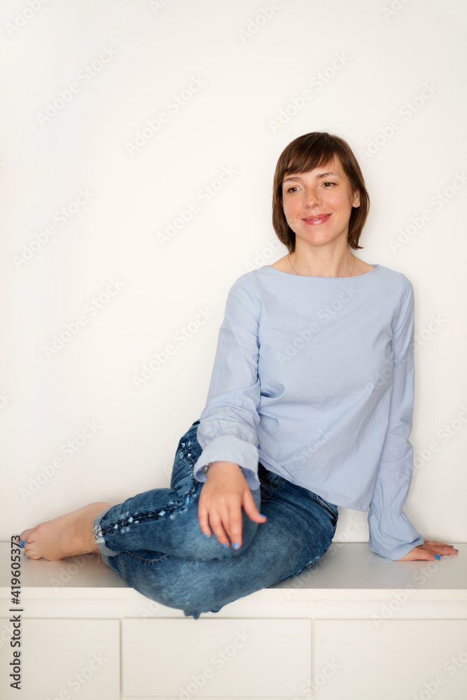 Woman sitting on a bench with her bare feet tucked