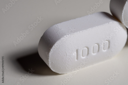 Heap of pills lying in front of two closed lying sideways and some pills in it. Pills are white. photo