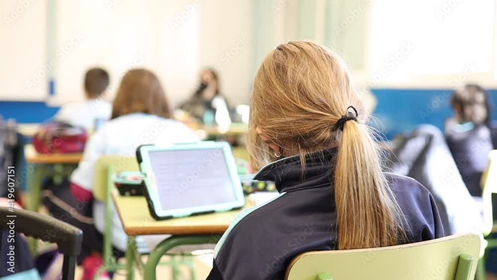 unrecognizable young girl in class working with tablet at her desk in school