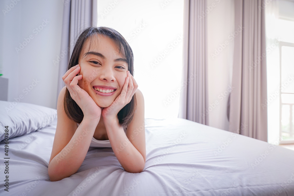 Happy young Asian woman waking up on her bed Happy young Asian woman waking up on her bed