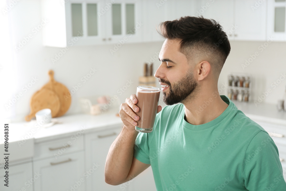 Young man drinking chocolate milk in kitchen