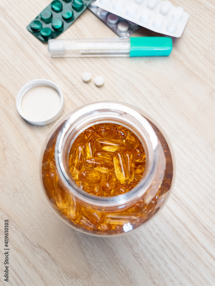 Yellow pills spilling in drug bottle, close-up. Top down view. Colorful tablets with capsules. Medical and health concepts.