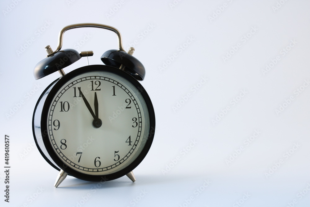 Retro alarm clock showing five minutes to twelve isolated on white background, concept Retro alarm clock showing five minutes to twelve isolated on white background, concept
