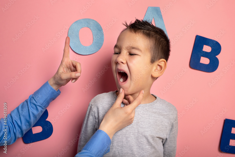 Portrait of a 4 year old boy speech therapy concept on pink background. Correct pronunciation