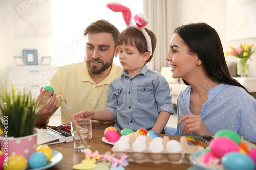Happy family painting Easter eggs at table indoors