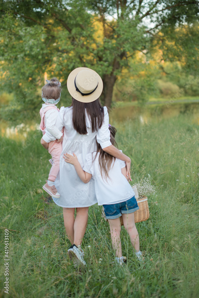 mom and daughters walk in nature by the pond in the summer