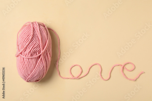 Word Love made with pink thread and woolen yarn on beige background, top view. Space for text