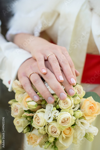 the bride and groom hold hands with rings over the wedding bouquet