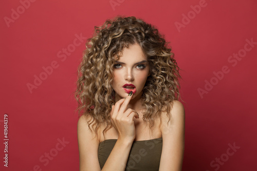Sensual woman with perfect curly hair on red background