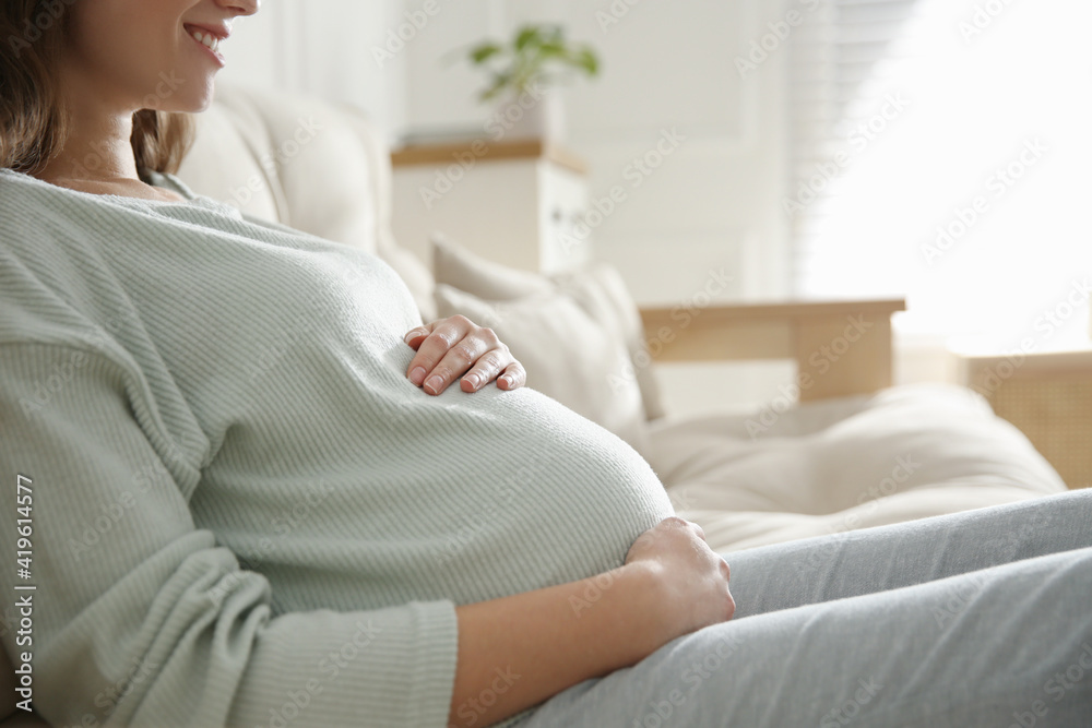 Pregnant woman touching her belly indoors, closeup Pregnant woman touching her belly indoors, closeup