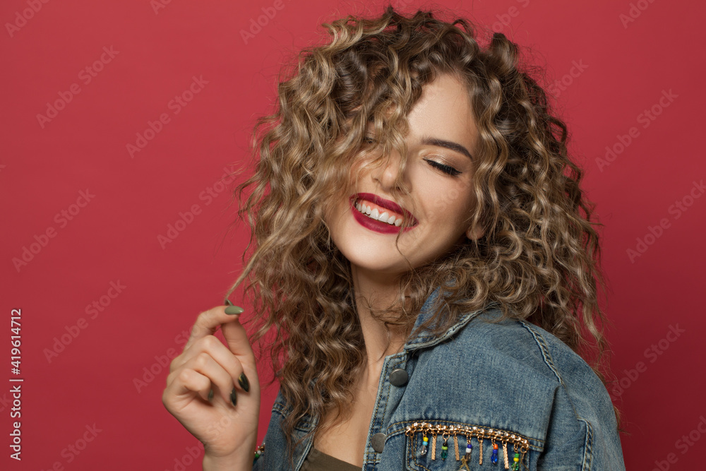 Happy young woman with curly hairstyle on red background Happy young woman with curly hairstyle on red background