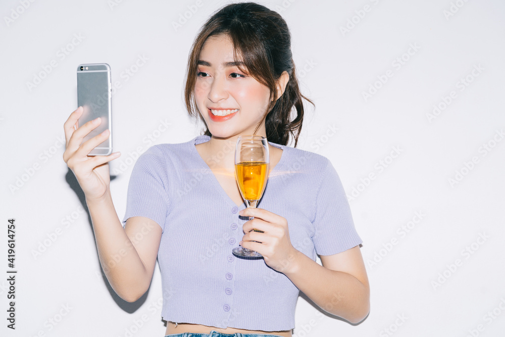 Young Asian woman drinking wine and using smartphone on white background Young Asian woman drinking wine and using smartphone on white background