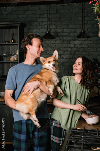 Happy caucasian couple cooking food at kitchen with their corgi dog. Young family, woman and man have a dinner © romanovad